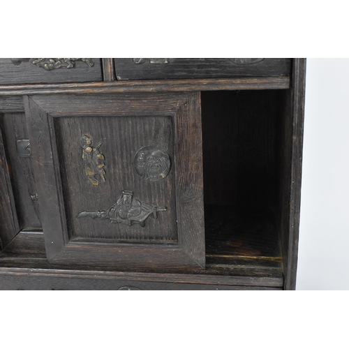 73 - A Japanese Meiji period table top cabinet, late 19th century, in dark oak, with two short drawers ab... 