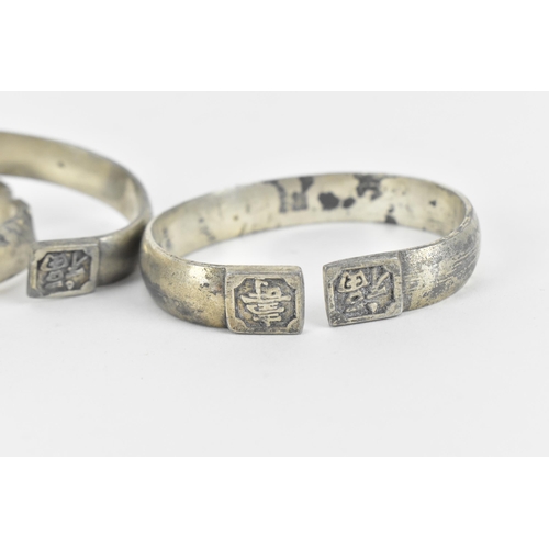 80 - A set of three Chinese white metal torque bangles, with stamped character hallmark, designed with dr... 