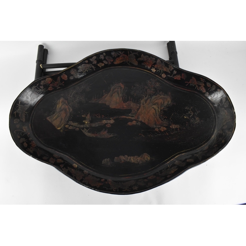 77 - A 19th century Chinese black lacquered tray on stand, the shaped tray with red and faded gilt natura... 