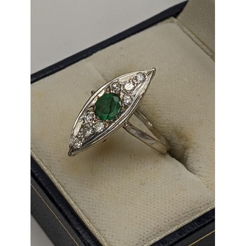 116 - A white metal Art Deco inspired Lozenge shaped ring having a central emerald surrounded by diamonds,... 