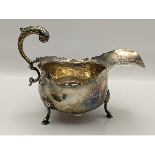 60 - An early 20th century silver sauceboat having a scroll shaped handle and on three horse hoof shaped ... 