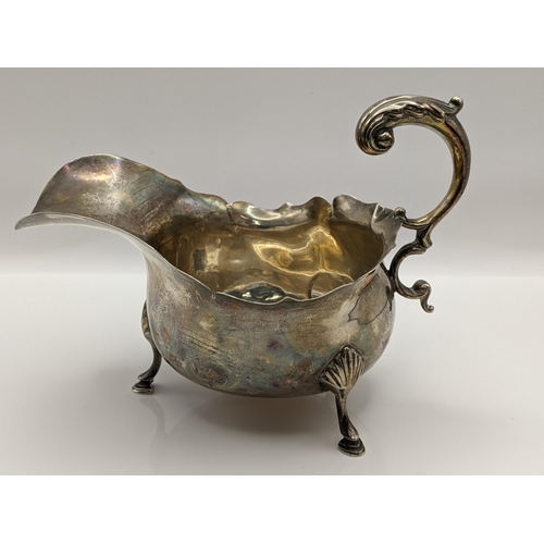 60 - An early 20th century silver sauceboat having a scroll shaped handle and on three horse hoof shaped ... 