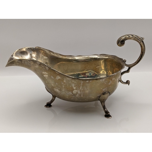 61 - An early 20th century silver sauceboat having a crimped edge and scroll shaped handle hallmarked 192... 