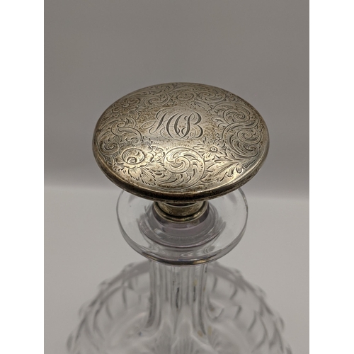 80 - A sterling silver topped squat formed decanter, to stopper engraved with initials and a floral desig... 