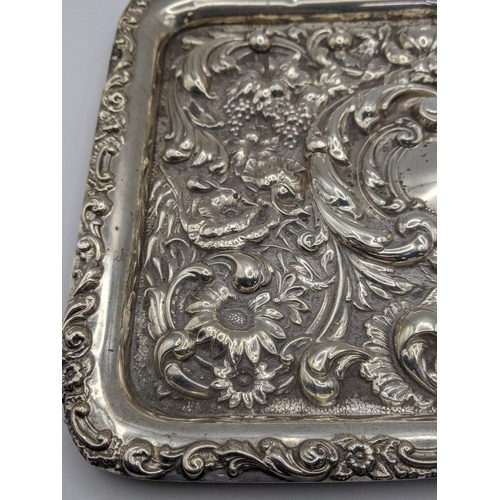 68 - An early 20th century silver embossed rectangular shaped tray decorated with flowers and C-scrolls, ... 