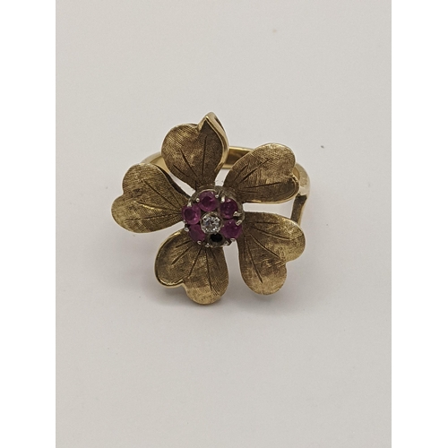 9 - A yellow metal ring in the form of a flower inset with a diamond and purple rubies A/F, total weight... 