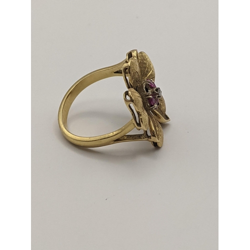 9 - A yellow metal ring in the form of a flower inset with a diamond and purple rubies A/F, total weight... 