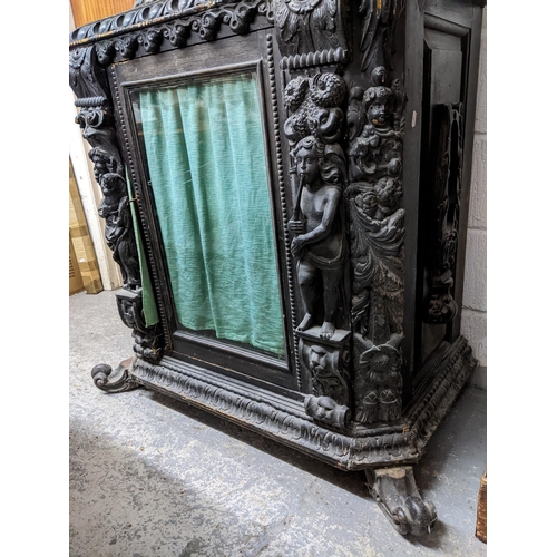 152 - A 19th century ebonized and parquetry carved wooden side cabinet, carved pediment over an arched ope... 