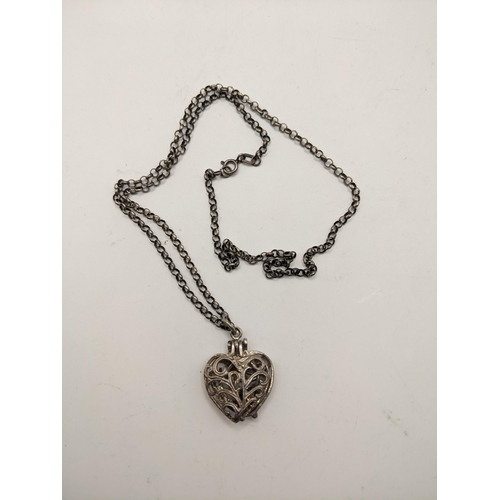 108 - A silver pendant fashioned as a heart opening to reveal a ring, with pierced scrolled ornament on a ... 