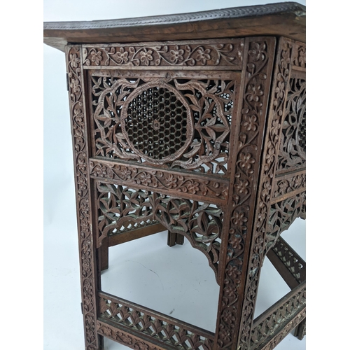 77 - An early 20th century Indian carved hardwood table with hexagonal top on a folding base, 66cm high, ... 