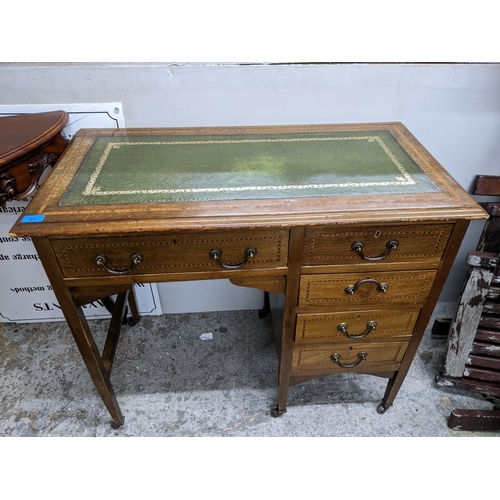 91 - An early 20th century inlaid walnut knee hole desk, the top with gilt tooled inset green leather scr... 