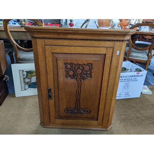 106 - An arts and crafts oak wall mountable corner cabinet with a carved image of a tree to the door
Locat... 