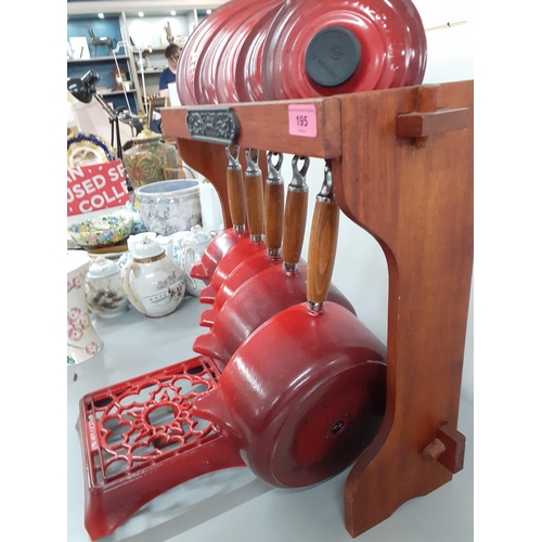 195 - A set of five Le Creuset red flame graduating enamelled saucepans with lids on a saucepan stand toge... 