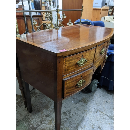 202 - A Georgian mahogany bow fronted kneehole sideboard with brass top rail, inlaid stringing, later bras... 