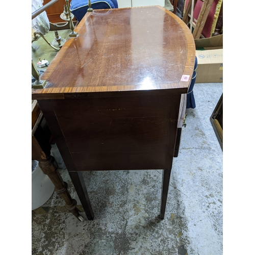 202 - A Georgian mahogany bow fronted kneehole sideboard with brass top rail, inlaid stringing, later bras... 