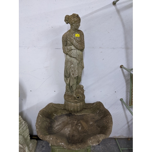 325 - A weathered concrete stone garden fountain in the form of a classically dressed maiden with a vase b... 