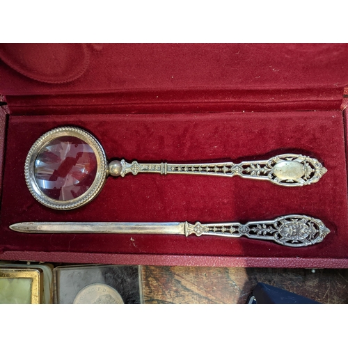 219 - Eight hundred continental silver letter opener and magnifying set, cased with commemorative coins to... 