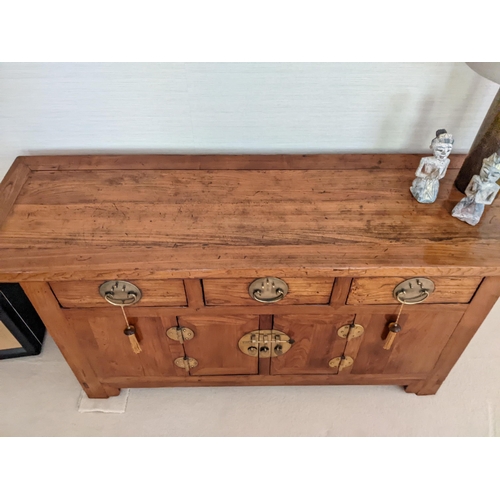 271 - A Chinese elm alter cabinet with three in line drawers and a pair of door with brass fittings and ov... 