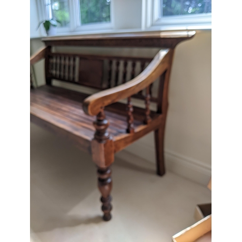 289 - A Thai stained softwood bench with a carved and spindle back and slatted seat on turned legs, 128cm ... 