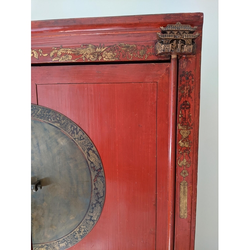 291 - A Chinese red lacquered marriage cabinet with gilt ornament and brass fittings, enclosing shelves an... 