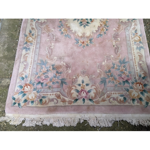 112 - A Chinese pink ground rug having a central motif and a floral design, 250c,m x 153cm
Location:G