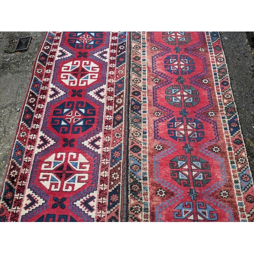 114 - A matched pair of Persian hand woven runners having a red ground with repeating motifs, 284cm x 72cm... 