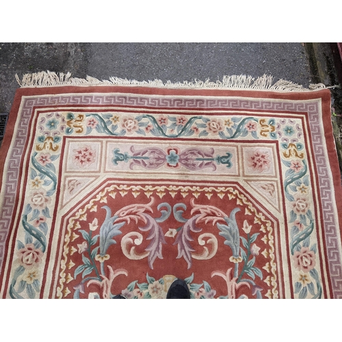 116 - A Chinese red ground rug having a central motif and multi-guard borders, 280cm x 182cm
Location:G