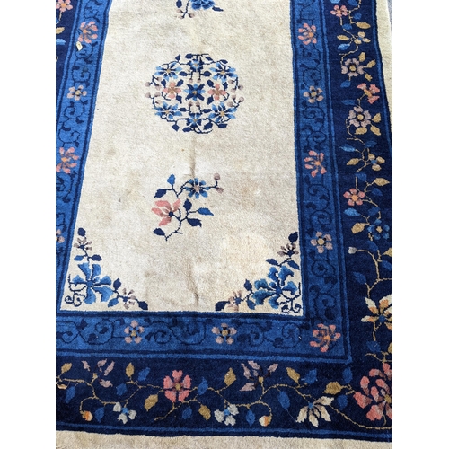 205 - A Chinese handwoven Peking rug having a central motif and a floral border 180cm x 118cm Location:G