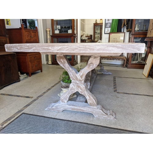 275 - A limed panelled wood effect refectory table on cross-over supports and arched feet, by Oka 100% wea... 