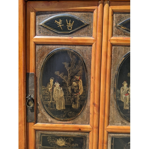 374 - A Chinese black lacquered pine marriage cabinet with four panelled doors decorated with figures and ... 