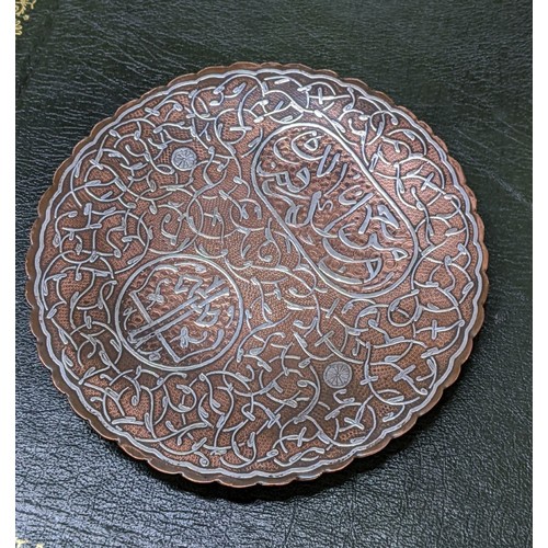 196 - An Islamic, Cairo, inlaid silver on copper dish, with panels of text and scrolls, on three ball feet... 