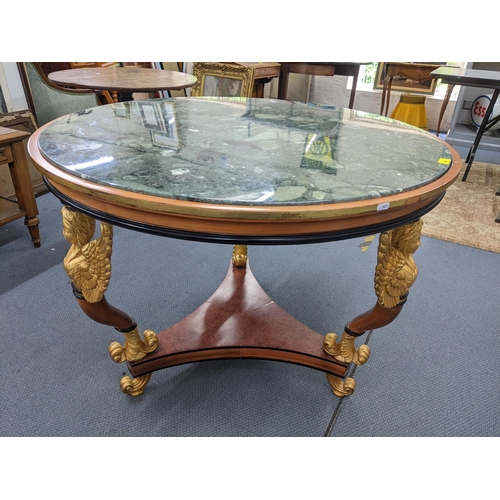 226 - An Empire style circular topped table having a marble effect top, supported by three winged angels a... 