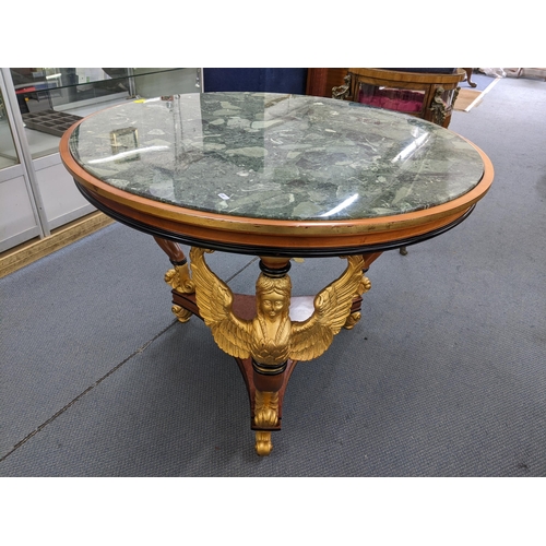 226 - An Empire style circular topped table having a marble effect top, supported by three winged angels a... 