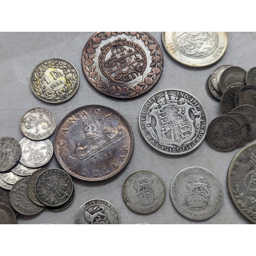 322 - A mixed group of early 20th century coins to include a 1935 Canadian silver Dollar, Egyptian 20-Qirs... 