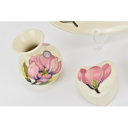 137 - A collection of Moorcroft pottery pieces in the 'Magnolia' pattern, comprising a lidded heart-shaped... 