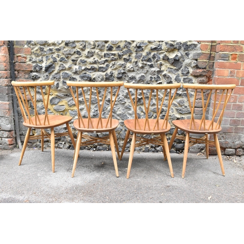 150 - A set of four Ercol candlestick back dining chairs, in light beech and elm, on tapering legs joined ... 