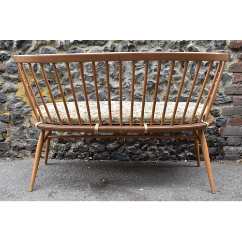 152 - A mid century elm and beechwood Ercol loveseat, with cushion, spindle back, raised on tapered turned... 