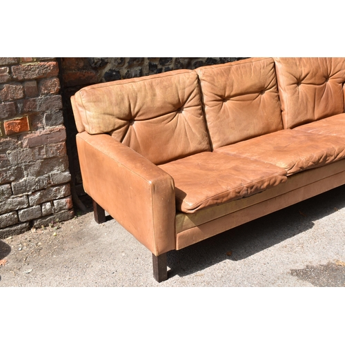 166 - A mid century design three-seater brown leather sofa, in the style of Georg Thams, with buttoned bac... 