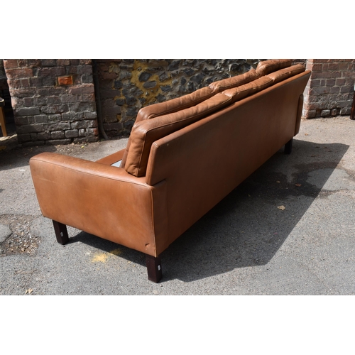 166 - A mid century design three-seater brown leather sofa, in the style of Georg Thams, with buttoned bac... 