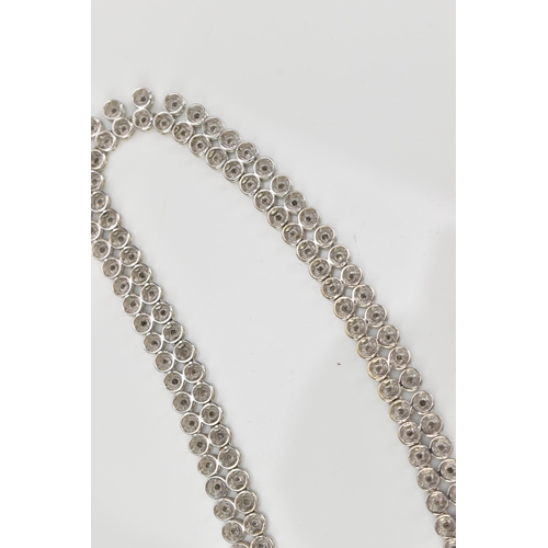 287 - An 18ct white gold and diamond necklace, designed with a double row of flat circular links centered ... 