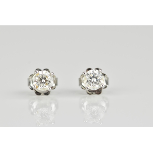 290 - A pair of solitaire diamond earrings, the brilliant cut stones approx 0.30 carat, in a four claw set... 