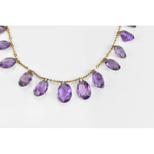 298 - A yellow metal and amethyst fringe necklace, set with graduated faceted oval cut amethyst drops, on ... 