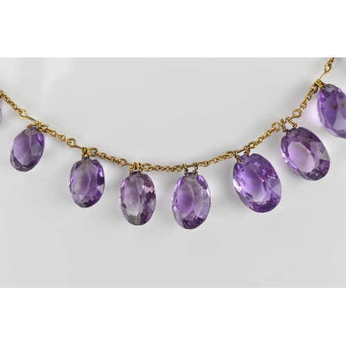 298 - A yellow metal and amethyst fringe necklace, set with graduated faceted oval cut amethyst drops, on ... 