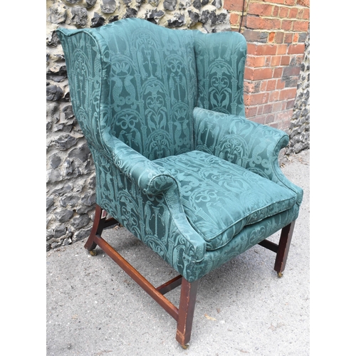 419 - A George III mahogany wingback armchair, early 19th century, upholstered in green brocade with mythi... 