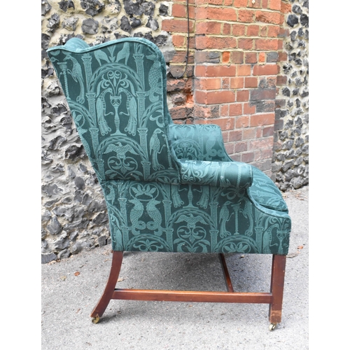 419 - A George III mahogany wingback armchair, early 19th century, upholstered in green brocade with mythi... 