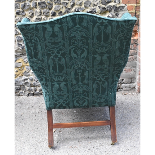 419 - A George III mahogany wingback armchair, early 19th century, upholstered in green brocade with mythi... 