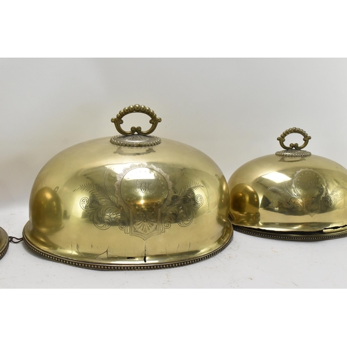 422 - A graduated set of Victorian brass meat covers, with beaded rim and hoop handles, the front of each ... 