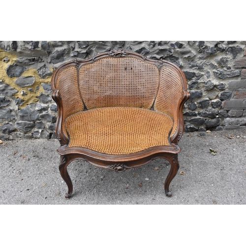 425 - A Louis XV style canned bergère armchair, with curved backrest, the carved rail with central rocaill... 