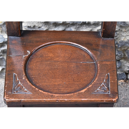 427 - A 17th/18th century carved oak Derbyshire style correction chair, with pierced shaped cresting rail ... 