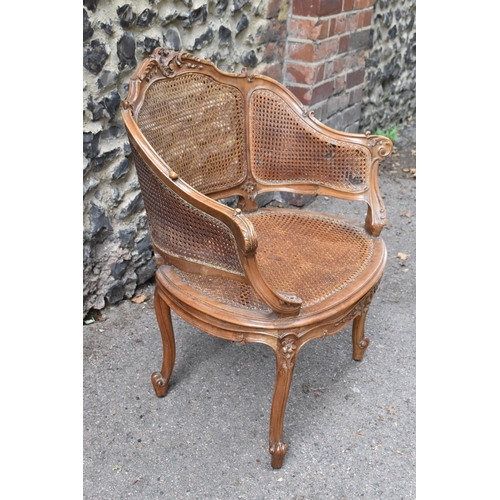 428 - A Louis XV style canned bergère armchair, with curved backrest, the carved back rail with central ro... 